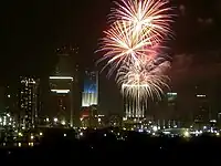 Tower lit as American flag on 4th of July, showing fireworks in foreground