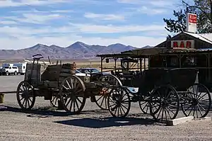 Two wagons in front of a wooden building with a surrounding patio.