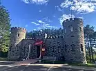 Exterior of stone Castle-like building. One story with two towers on either end.