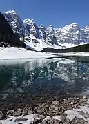 Moraine Lake is still mostly frozen in May and a considerable amount of snow is still in the area and the surrounding mountains.