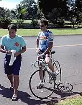 A man on straddling a bike in sunglasses.