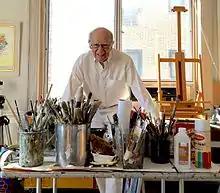 Man standing behind desk of art supplies