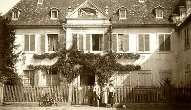 Black and white photograph of a classical building preceded by a walled garden.