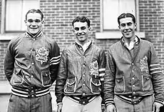  three young men stand side by side.  Each has short, dark hair parted in the middle and are wearing identical team jackets with a stylized maple leaf logo on the left breast.