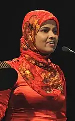 Sheela holding an award and giving a speech