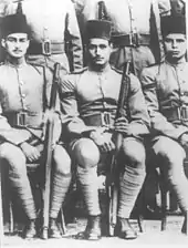 Two seated men in military uniform and wearing fez hats