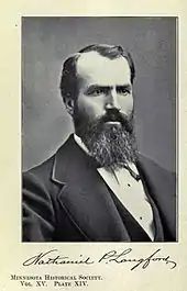 A middle-aged man in formal attire with a beard