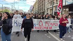 Photo of Greek university students marching down a street holding a banner