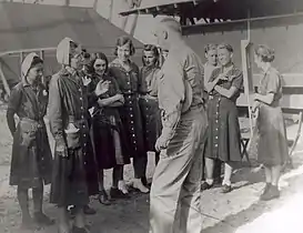 Navy nurses wearing makeshift denim uniforms, standing in a group outdoors, speaking to a man in uniform.