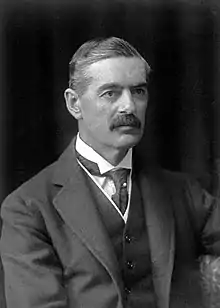 A black and white mid-length photograph of Neville Chamberlain, a man wearing a dark waistcoat and with a grey moustache, looking to the left.