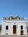 Trullo house with raised façade wall hiding both its conical roofs (Alberobello)