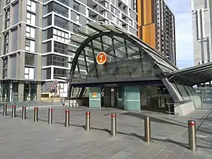 Picture of North Ryde station from the outside. It consists of a small entrance building, with most of the station below ground and not visible in the image.