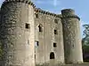 Ruined stone castle with round towers at each corner.