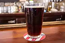 A pint glass filled with brown ale