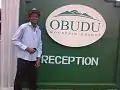 A man posing by the gate of Obudu Mountain Resort