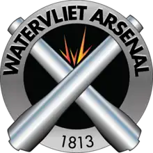 Distinctive unit insignia of the U.S. Army Watervliet Arsenal featuring a silver ring around two crossed cannons with a spark above where they cross signifying the manufacturing nature of the arsenal.