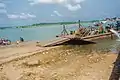 Bank of Oguta Lake showing human activities such as motorcycle washing and transportation of goods and people.