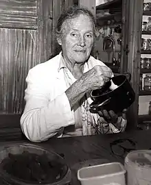 Bauermeister holding a pot in her kitchen while smiling for the camera