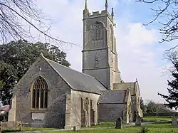 Stone building with prominent square tower. In the foreground are gravestones.