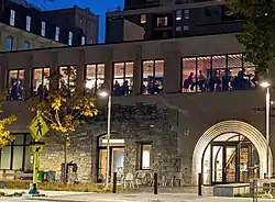 Diners seen in silhouette on second floor of a stone and brick building at night