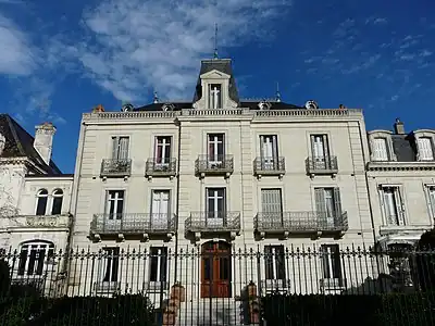 The entire house, white, two storeys high and five windows wide, with its fence.