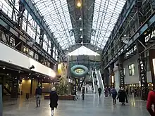 Large atrium with two escalators, the base of a tree, and industrial features