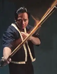 Edgar Sulite seen wielding a staff and performing a martial arts move