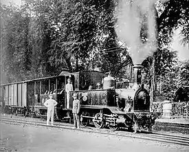 Three colonial Europeans and three local railway employees in front of a steam locomotive