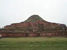 Image 32alt=Ruins of a structure of red stone now resembling a small hill or mound. (from Culture of Bangladesh)