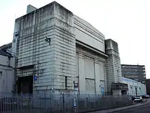 An unkept white building, which looks run down and in need of repair.