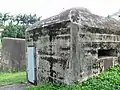 The entrance-door shown here together with one of the pillbox's gun embrasures.