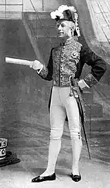 White man in court dress with gold frogging and cocked hat, on deck of sailing ship