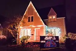 Photograph of a house at night, with a high, peaked roof outlined with decorative lights