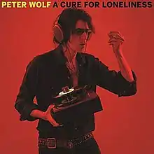 A red-tinted photo of Wolf listening to music through headphones plugged into a portable record player