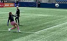 OL Reign goalkeeper Phallon Tullis-Joyce kicks a ball in the air while teammate Megan Rapinoe looks on