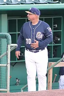 A man in a naby blue baseball jersey and cap with white pants