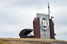 A park sign with a treasure chest next to it on top of a small hill