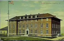 A color postcard showing a thee-and-a-half-story brick building with a pitched roof