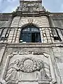 Entrance portal to the college, with reused 15th-century relief in foreground