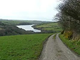 A road curving right with a lake in the middle distance