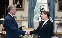 Ginsburg shaking hands with Carter as the two smile