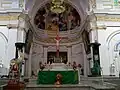 Central altar of the church with the bishop's cathedra visible on the right hand side covered with a green cloth