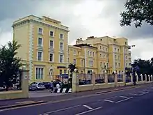 Photograph of front of Georgian-style white/cream Queen's Hotel building.