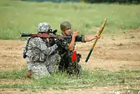 An American-Bulgarian team prepares to reload an RPG-7 shoulder-fired rocket launcher with a fresh rocket and booster charge.