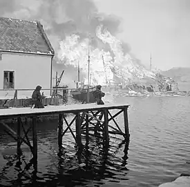 British troops watch an oil factory burn