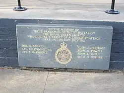 Oblong slate plaque with inscriptions in gold, set into a low wall