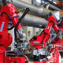 2 large industrial robots process material in a welding cell