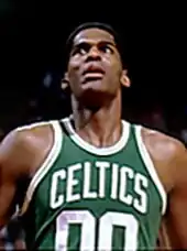 A man, wearing a green jersey with a word "CELTICS" and the number "00" written in the front, is looking up.