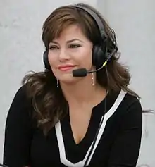 A woman with brunette hair, wearing a black and white top