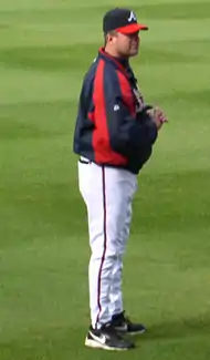 A man wearing a nylon navy blue and red warmup jacket and cap of the same colors